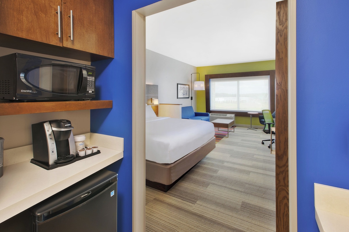 Una habitación de hotel con microondas, cafetera y una cama.
