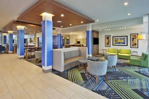 Un hall de hotel con área de descanso, una recepción y un televisor.