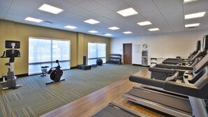 Un centre de remise en forme équipé de tapis de course, d’un appareil elliptique et de poids libres.