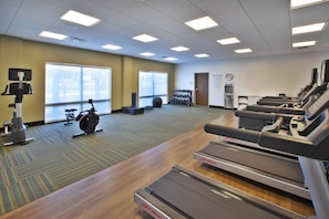 Et fitnesscenter med løbebånd, crosstrainer og vægte.