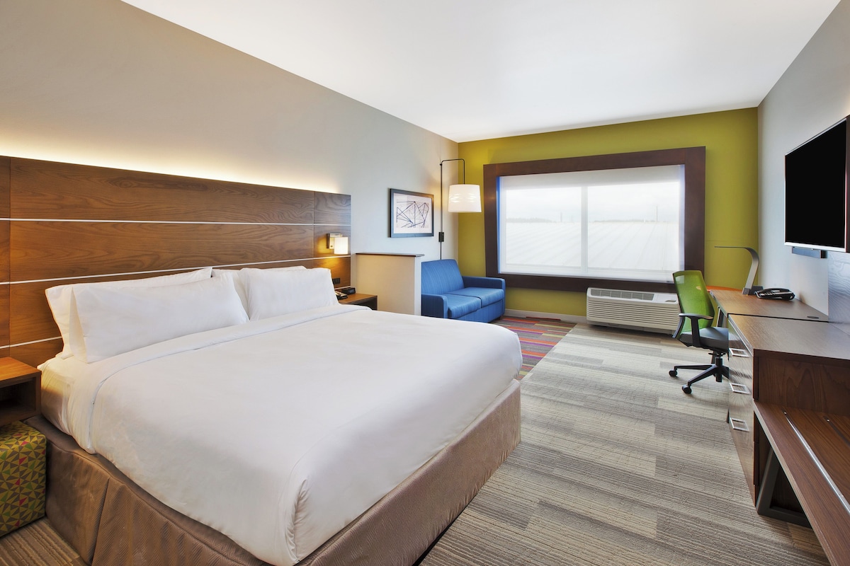 Una habitación de hotel con una cama grande, un escritorio, una silla, un televisor y una ventana.