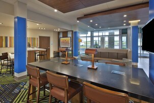 A hotel lobby with a large reception desk, seating area, and a view of the parking lot.