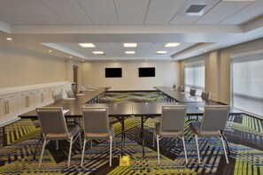 A conference room with a long table, chairs, a television, and a patterned carpet. - Holiday Inn Express & Suites South Hill by IHG (South Hill)