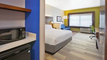 Une chambre d’hôtel équipée d’un lit, d’un bureau, d’une chaise, d’un four à micro-ondes et d’un petit réfrigérateur.