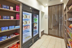 Un expositor refrigerado con diversos alimentos y bebidas, un estante con productos de higiene personal y una partición de madera.