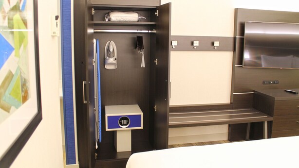 A hotel room with a minibar, a shoe rack, a coat rack, and a TV. - Holiday Inn Express & Suites St. Louis South - I-55 by IHG (St. Louis)