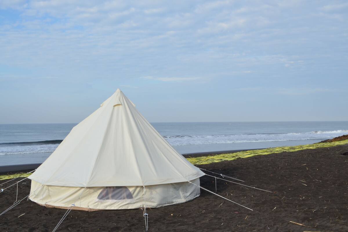 Una carpa blanca en la playa, con el océano al fondo.