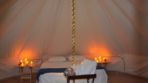 Une pièce chaleureuse avec un lit, des tables de chevet et des bougies.