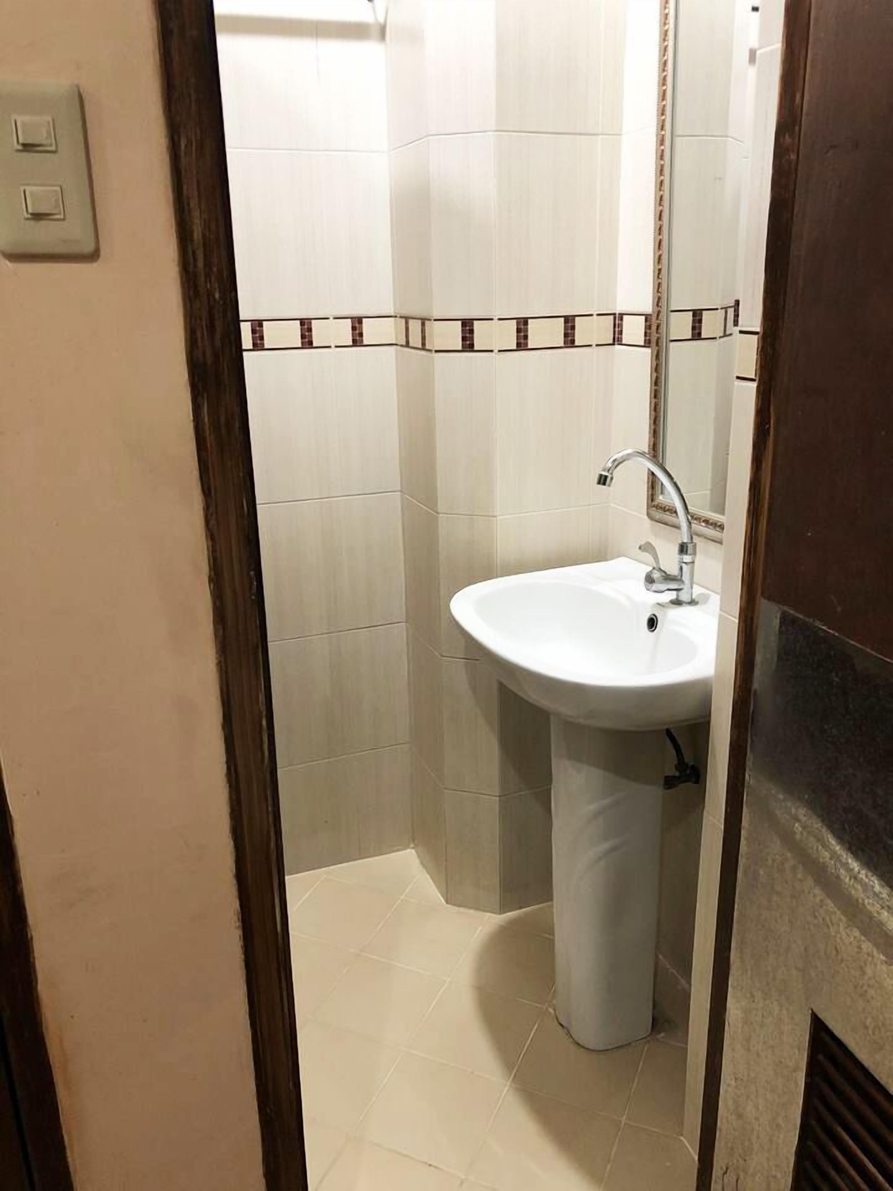 A small bathroom with a white sink, a mirror, and tiled walls.