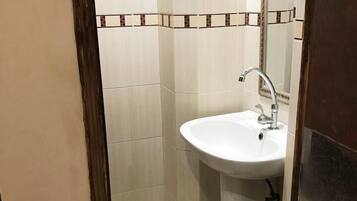 A small bathroom with a white sink, a mirror, and tiled walls.