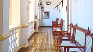 Un pasillo con baldosas de diseño, bancos de madera y candelabros colgantes.