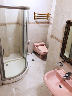 A bathroom with a glass-enclosed shower, a pink toilet, and a sink with a mirror. - My Vigan Home Hotel (Vigan)