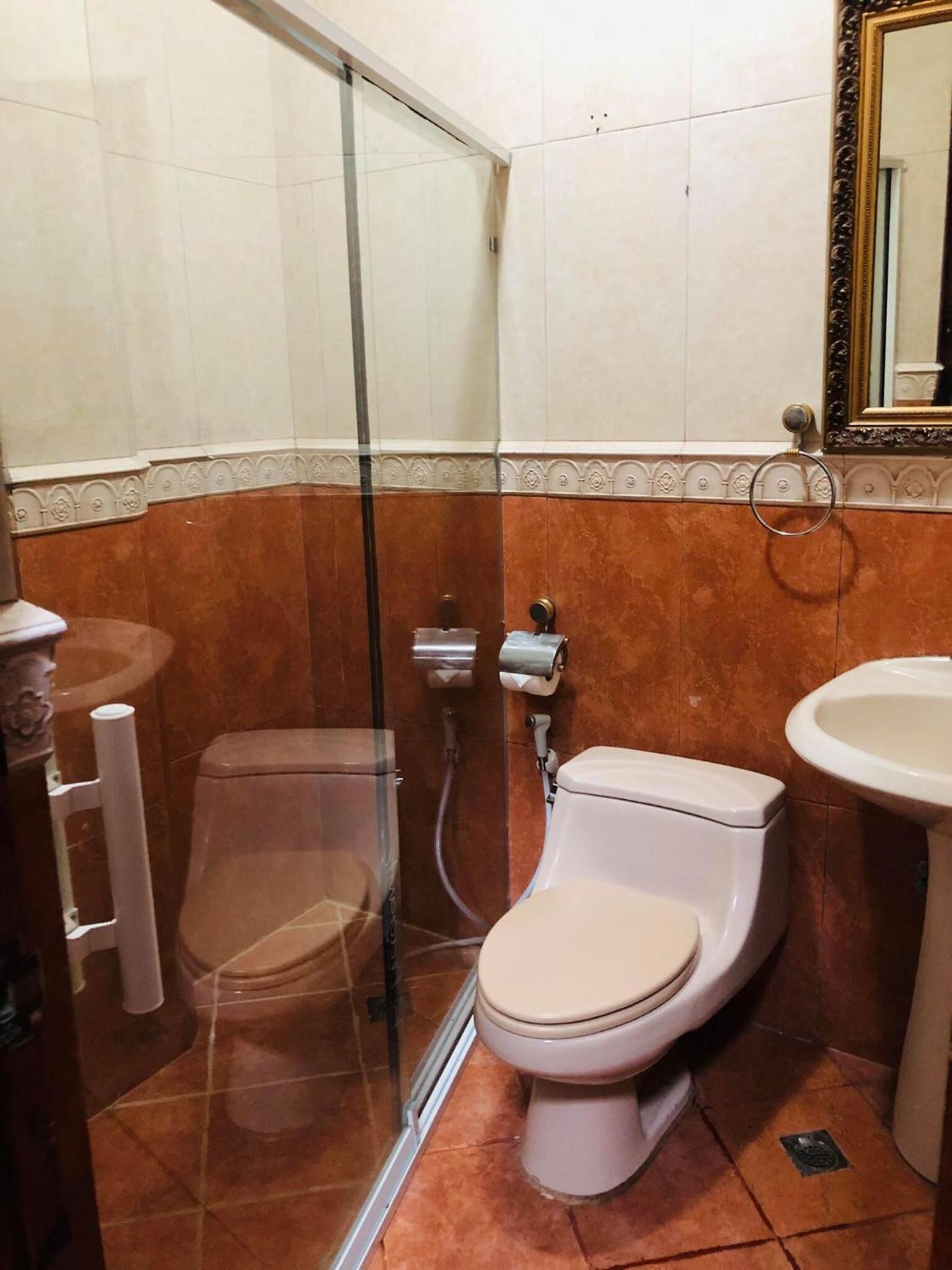 A bathroom with a glass shower enclosure, a toilet, and a sink.