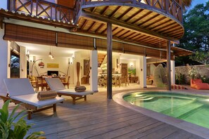 A wooden deck with lounge chairs and a pool. - Breezy Point Villas (Nusa Dua)
