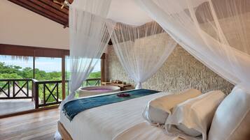 A bedroom with a large bed, white bedding, a view of the outdoors, and a balcony with a wooden railing.