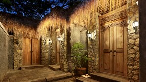 A stone building with wooden doors and steps, a thatched roof, and potted plants. - Breezy Point Villas (Nusa Dua)