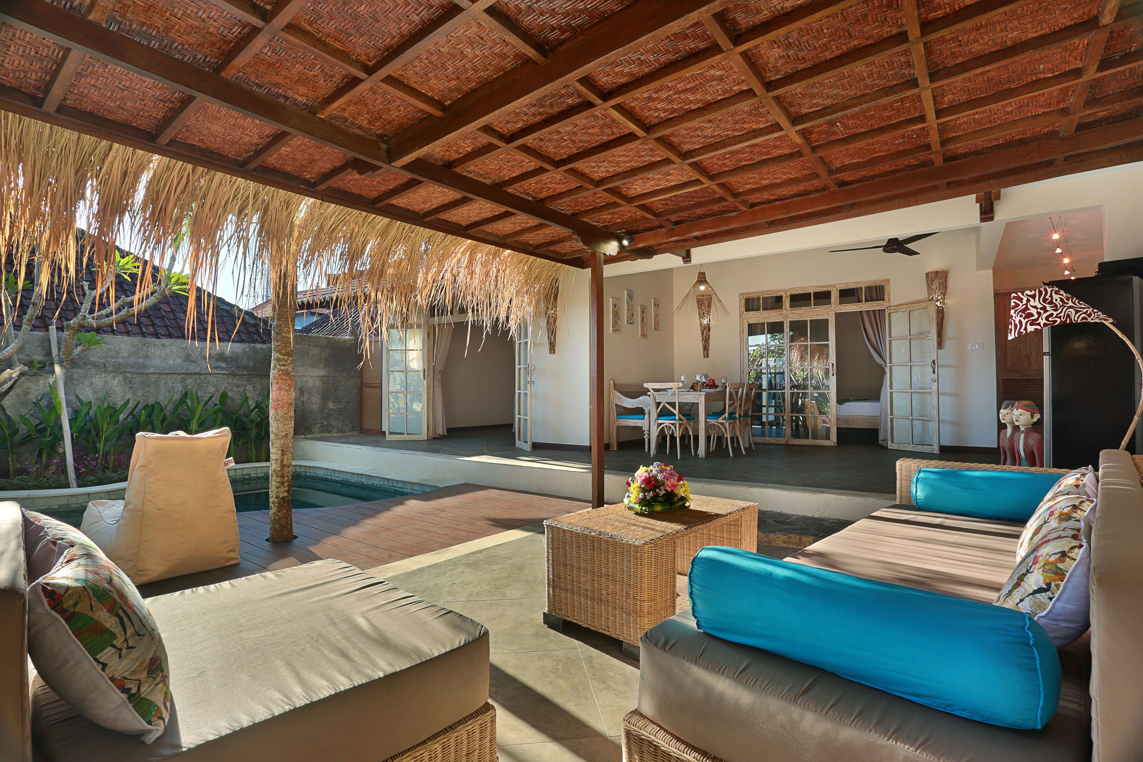 An outdoor lounge area with wicker furniture, a pool, and a covered patio.