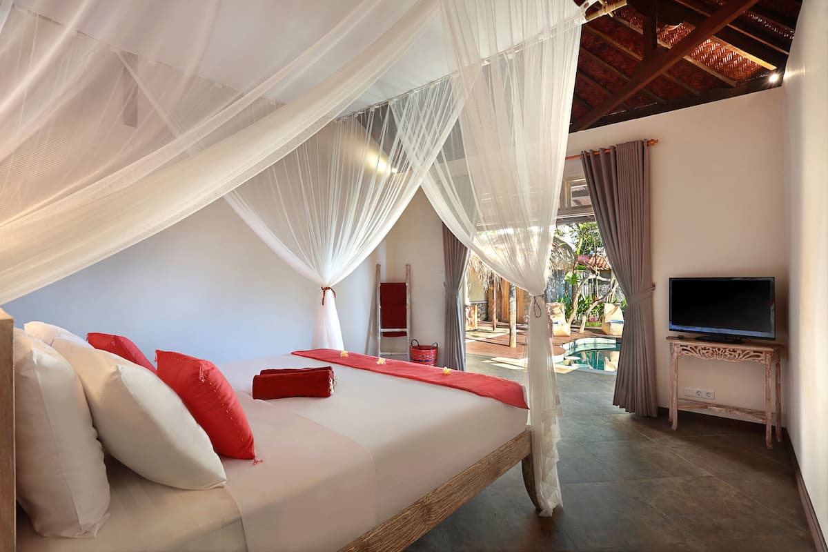A bedroom with a bed, a TV, and a view of the outside.