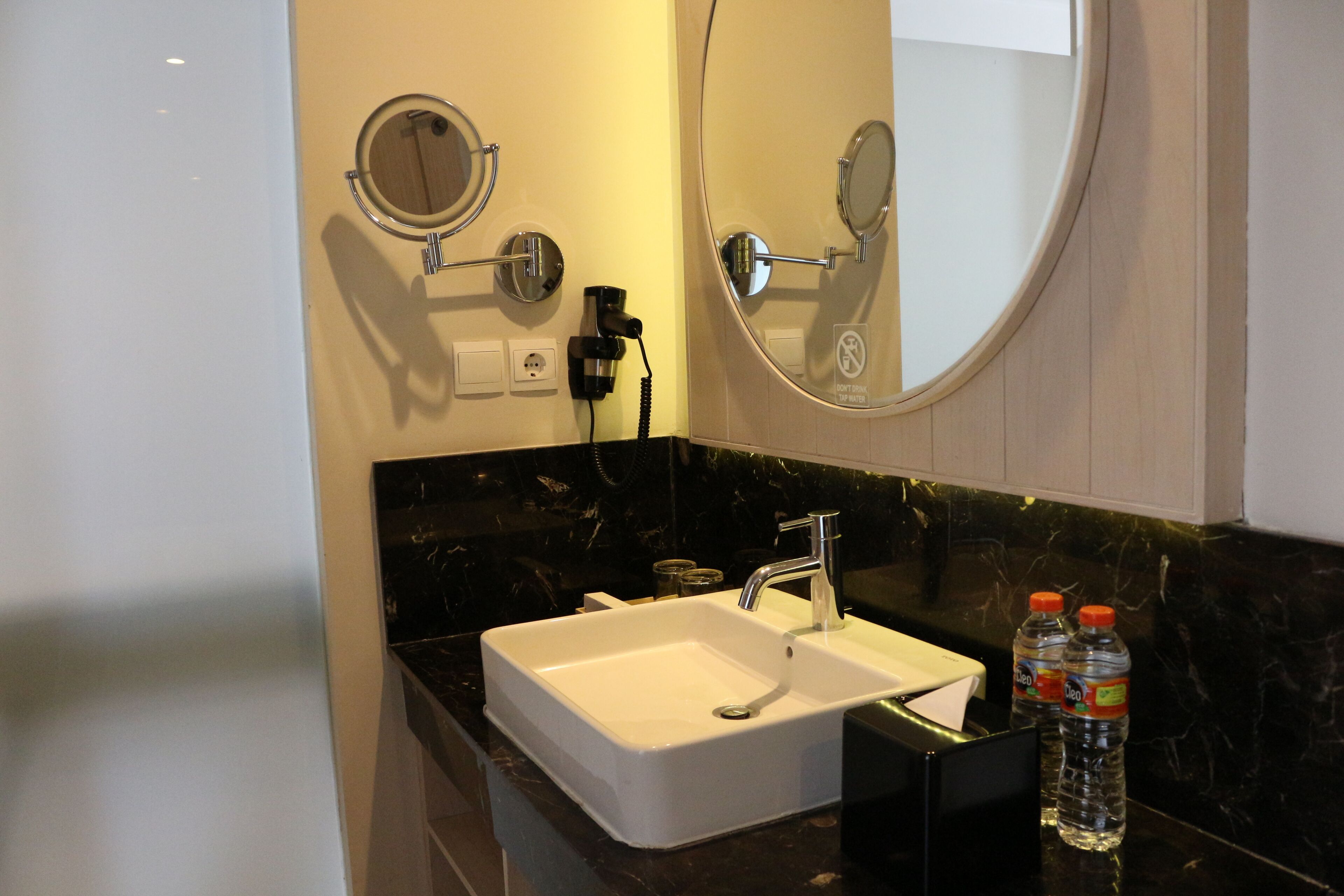 A bathroom with a white sink, a mirror, and two bottles of water on the counter.