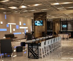 A modern hotel lobby with a long reception desk, multiple seating areas, and decorative wall panels.