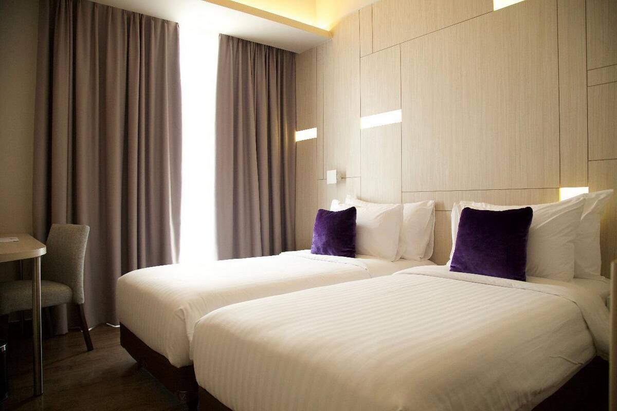 Ein Hotelzimmer mit zwei Betten, einem Schreibtisch und einem Stuhl.