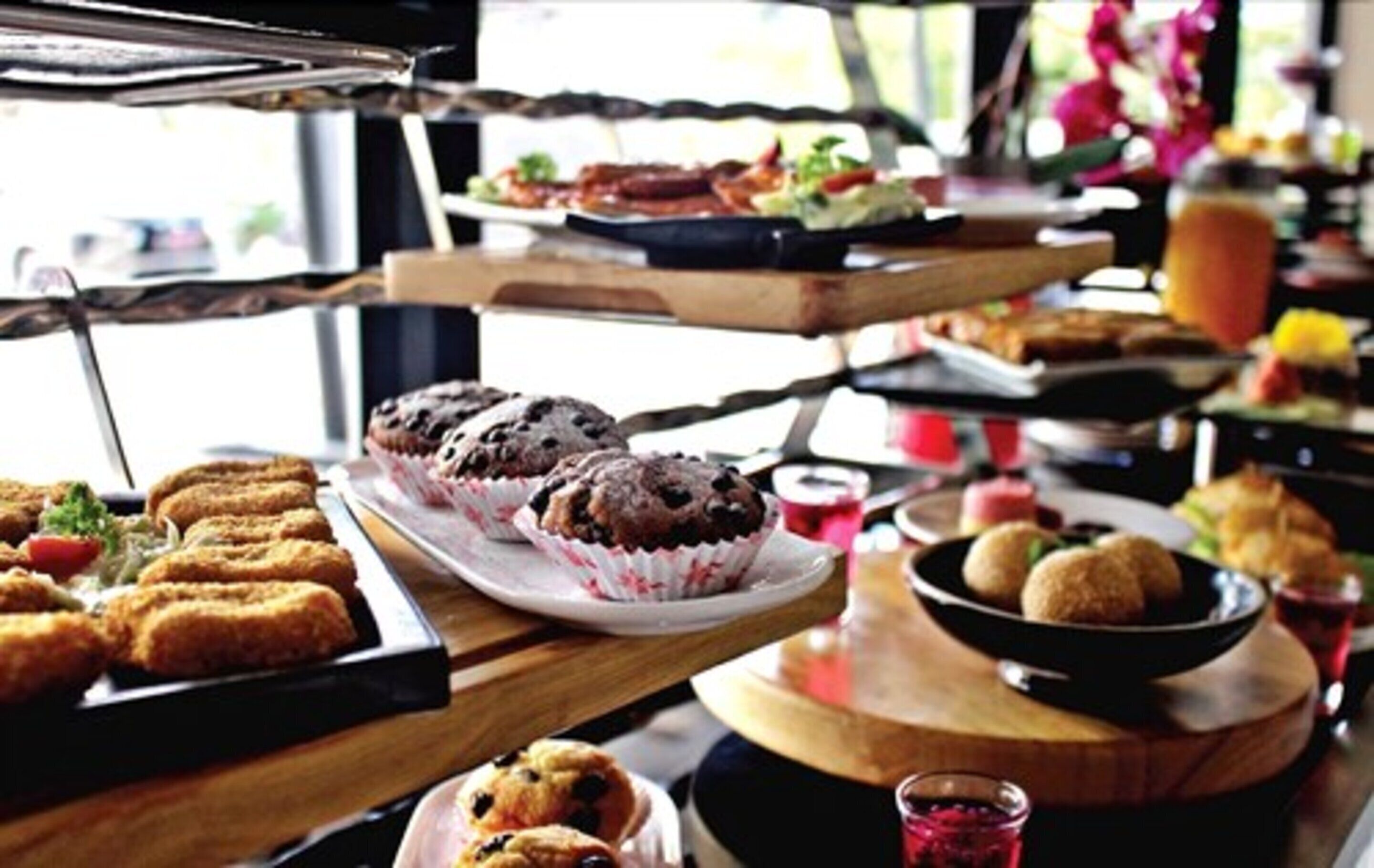A buffet table with various food items including muffins, pastries, and a bowl of round snacks.