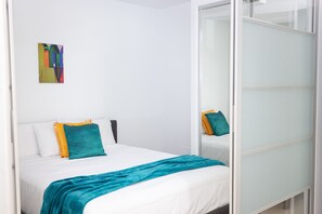 A modern hotel room with a bed, white walls, and a colorful artwork on the wall. - Nova Mooloolaba Beach (Mooloolaba)