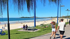 A beachside walkway with benches, a grassy area, and a view of the beach and ocean. - Nova Mooloolaba Beach (Mooloolaba)