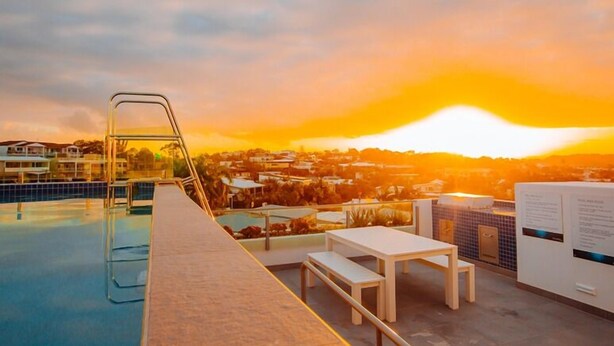 A rooftop pool with a view of a sunset over a residential area. - Nova Mooloolaba Beach (Mooloolaba)
