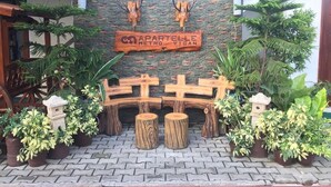 Un espace d’accueil avec un mur en pierre, des bancs en bois et des plantes en pot.
