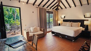 A bedroom with a large bed, a sofa, a dining table, and a view of the outdoors. - Kantawa Refugio de Bienestar (Jordán)