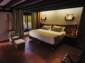 Une chambre à coucher comprenant un lit, une chaise, une table de chevet et donnant sur l’extérieur.