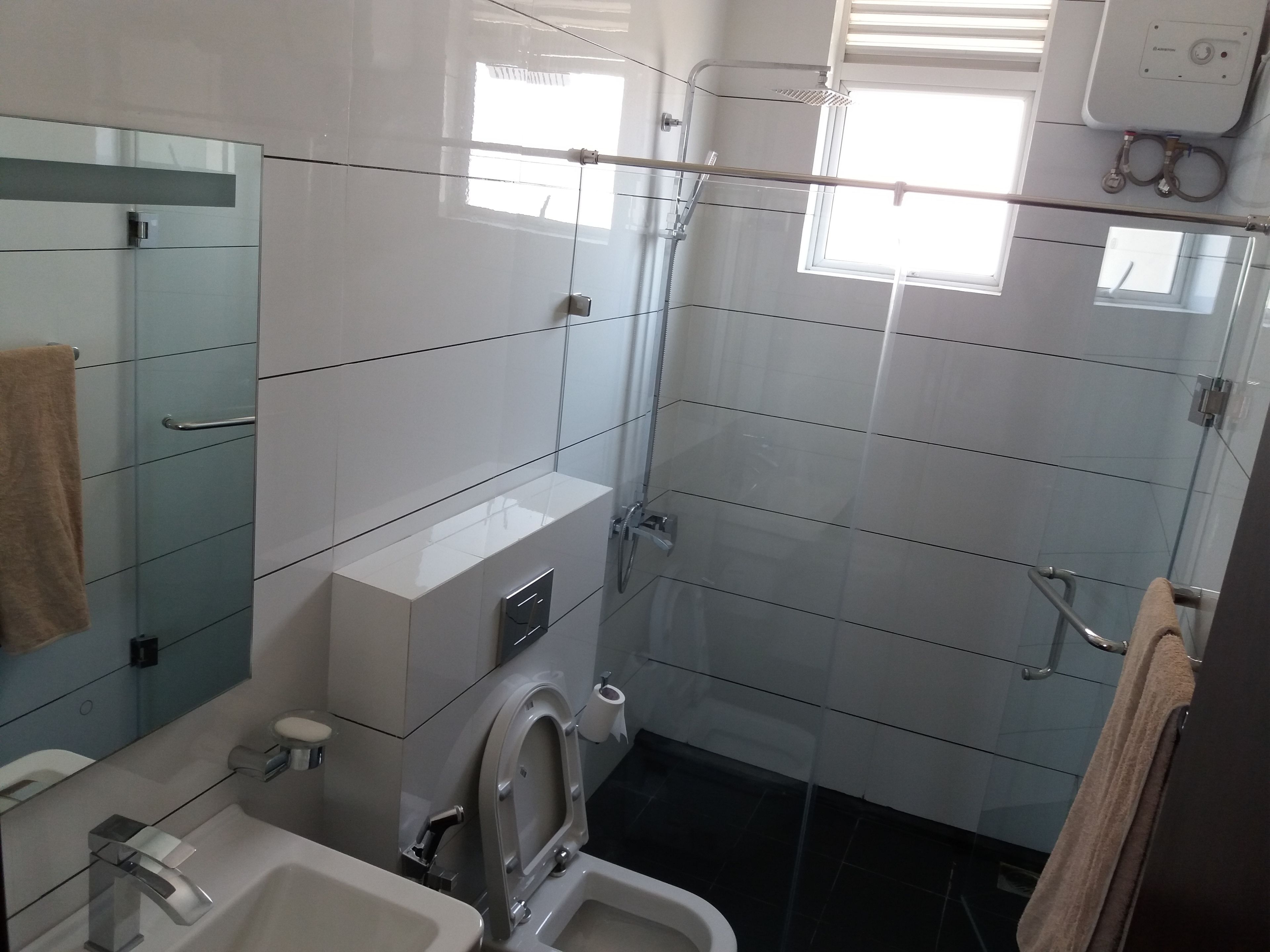 A modern bathroom with a glass shower enclosure, a toilet, and a sink.