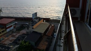 A view of the sea from a building with a red roof, a street with cars, and a building with a yellow roof. - Colombo Sea View Apartment (Colombo)