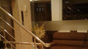 A staircase with metal railings leading to a landing, a brown sofa, and a vase with flowers on the landing. - Colombo Sea View Apartment (Colombo)
