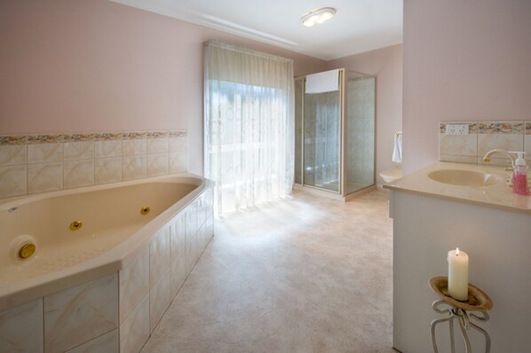A bathroom with a bathtub, a shower, and a vanity with a sink and mirror.