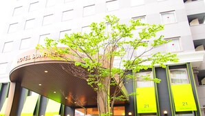 A modern hotel entrance with a large sign indicating room number 21. - Hotel Sunrise 21 (Higashihiroshima)