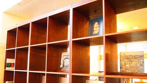 A wooden shelving unit with multiple compartments, some containing books and framed pictures. - Hotel Sunrise 21 (Higashihiroshima)