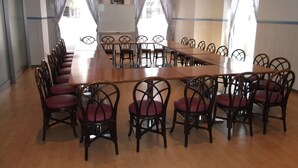 A conference room with a long table and chairs, large windows with curtains, and a chandelier. - Hotel Sunrise 21 (Higashihiroshima)
