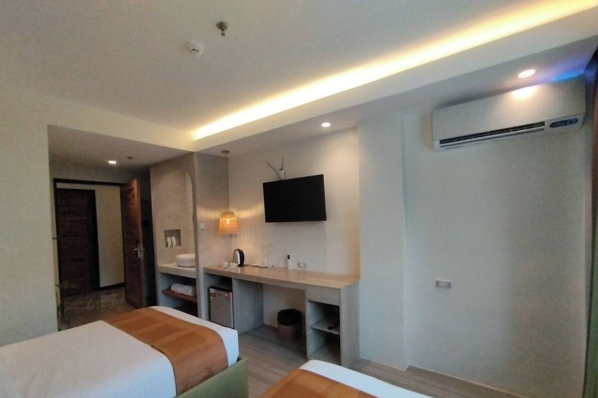 Habitación de hotel con dos camas, un escritorio, un televisor y un aire acondicionado.