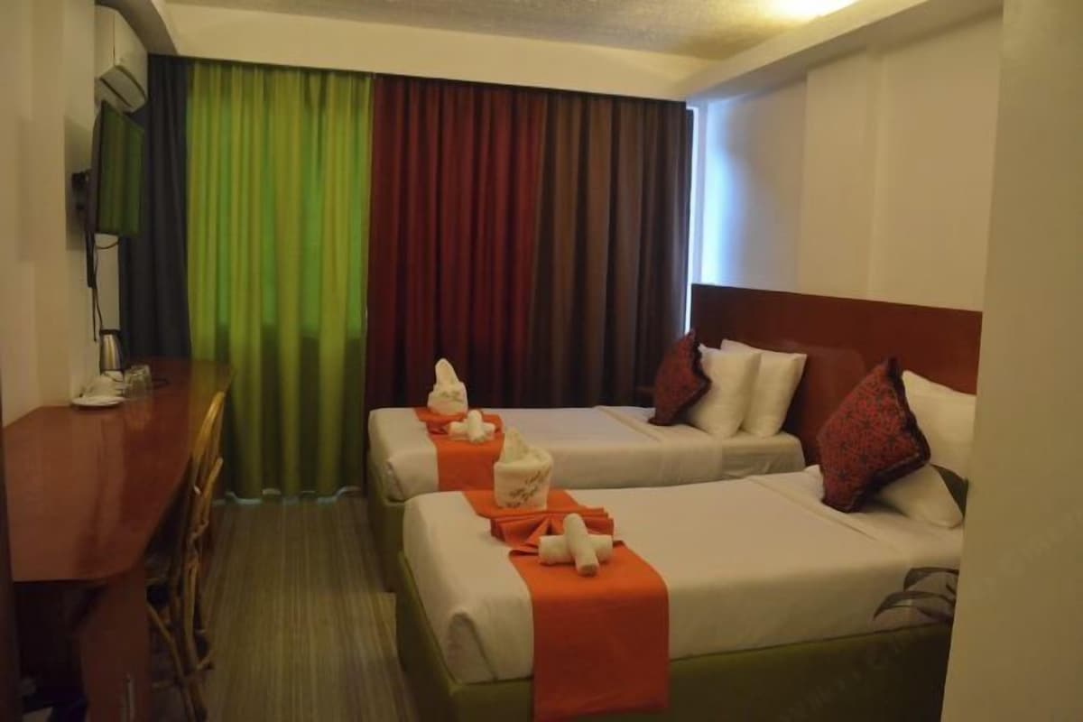 Ein Hotelzimmer mit zwei Betten, einem Schreibtisch und einem Stuhl.