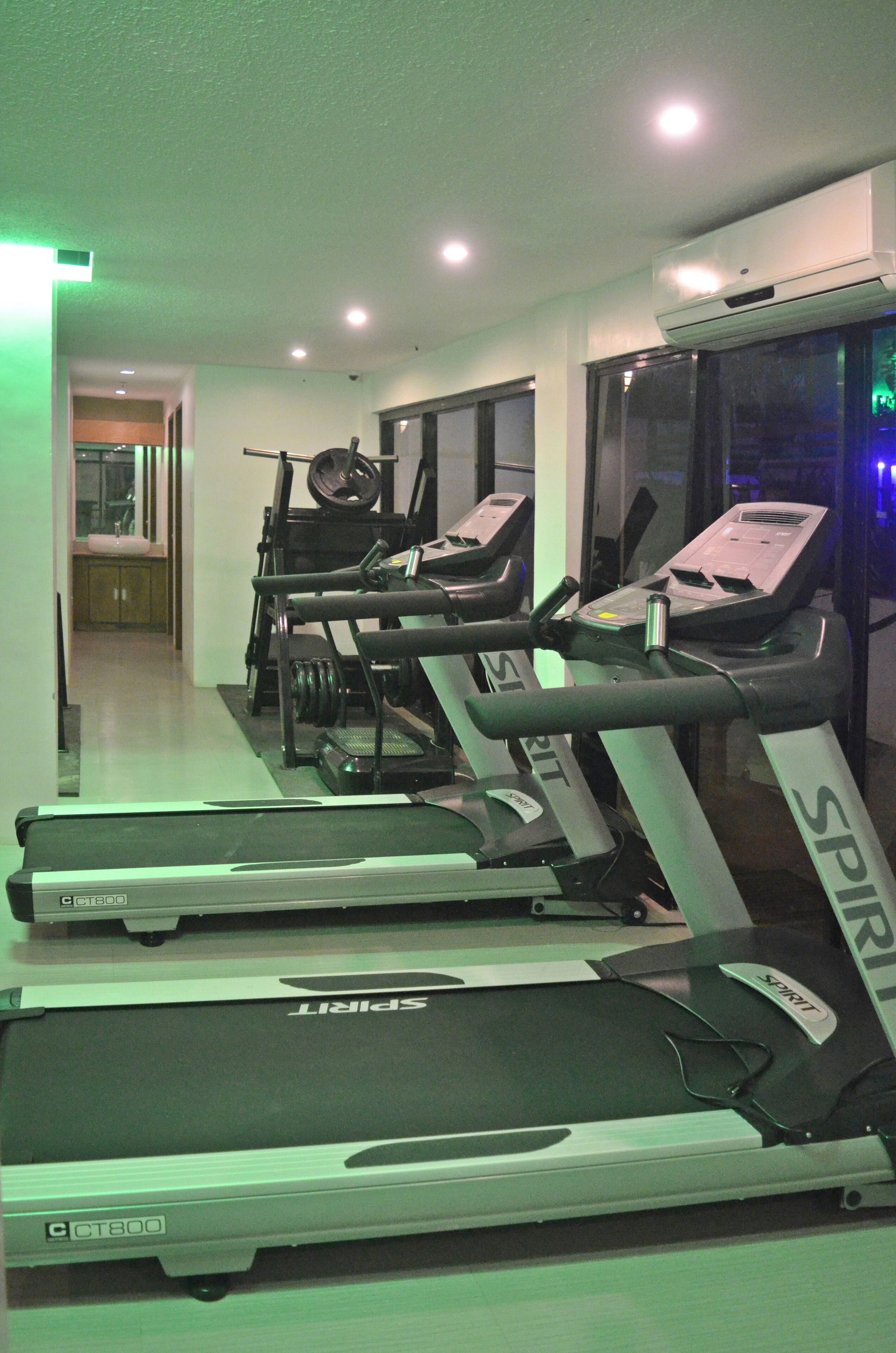 A gym with treadmills, exercise bikes, and a mirrored wall.