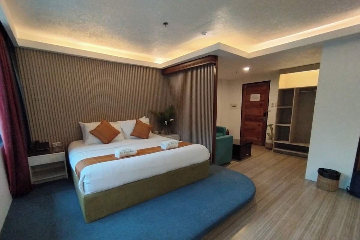 Una habitación de hotel con cama, escritorio, armario y cubo de basura.