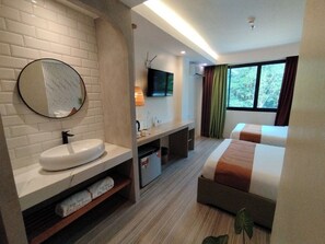 Une chambre d’hôtel avec une salle de bain, un lit, une télévision et une fenêtre avec des rideaux.