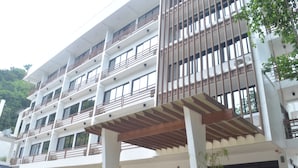 A multi-story hotel with balconies, a covered outdoor area, and a garden with various plants. - Villa Israel Eco Park El nido Palawan (El Nido)