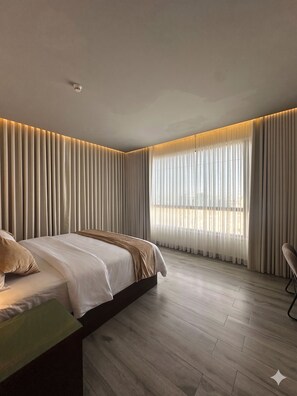 A modern bedroom with a bed, a chair, and a large window with curtains. - Rosalina Hotel (Yanbu)