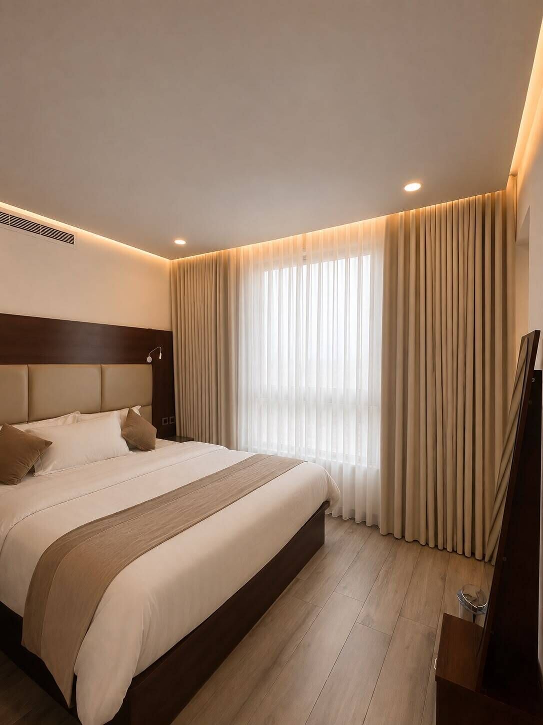 A hotel room with a bed, a TV, and a window with curtains.