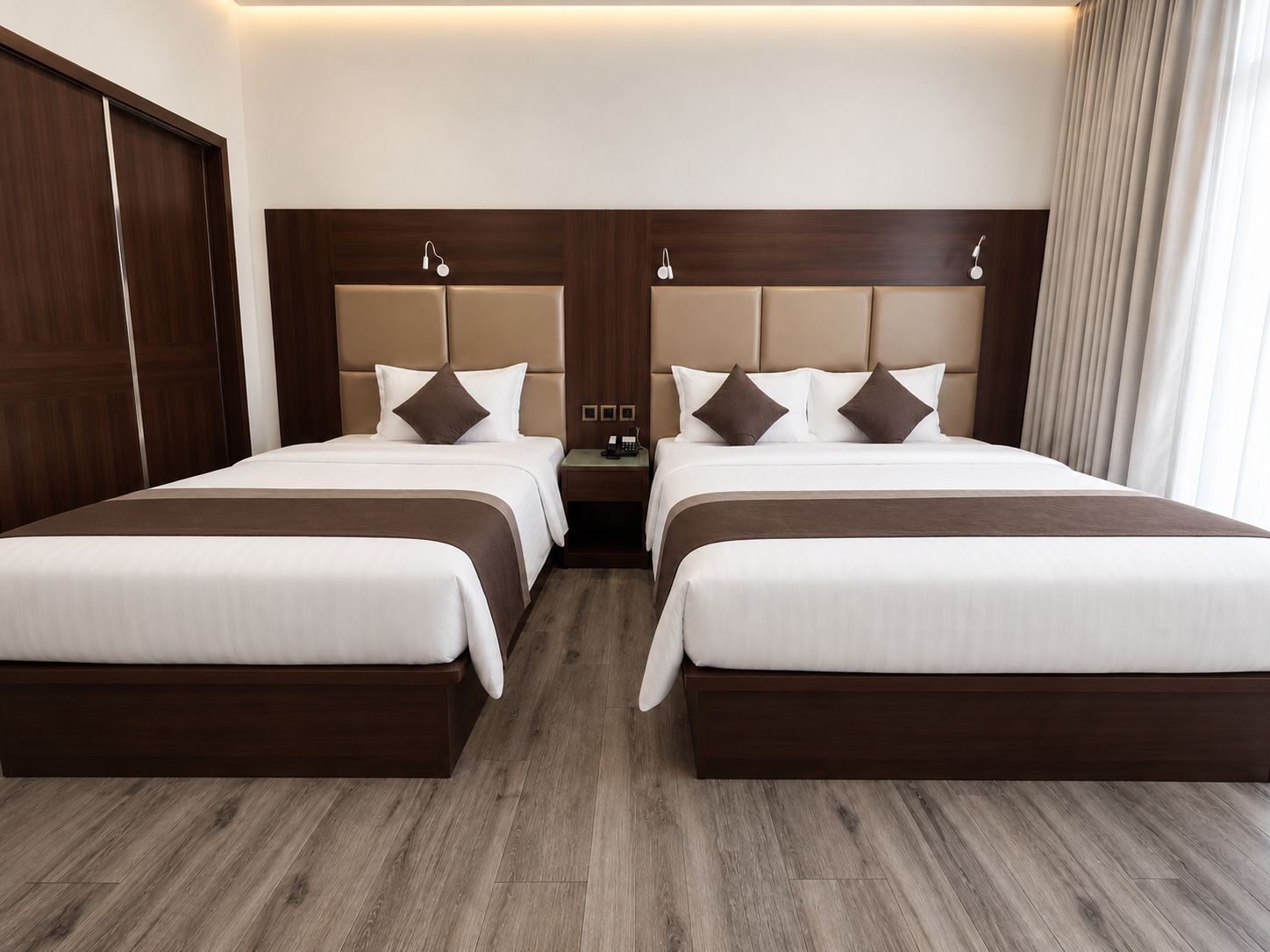 Habitación de hotel con dos camas, cabecero de madera, mesitas de noche y suelo de madera.