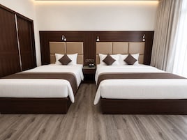 Habitación de hotel con dos camas, cabecero de madera, mesitas de noche y suelo de madera.