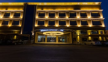 Um hotel com uma entrada ampla, várias janelas e uma placa de destaque.